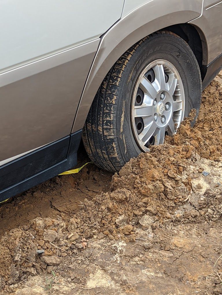 A car is stuck in the mud on a dirt road.