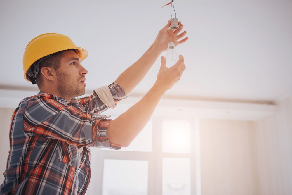 Installing light bulb — Level 2 Electrician Near Me in Kurri Kurri NSW