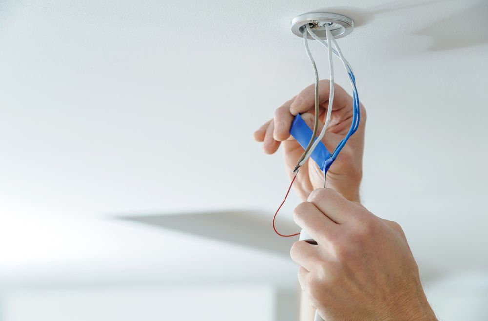 Man is using an insulating tape to the bare electric wires — Level 2 Electrician Near Me in Newcastle NSW