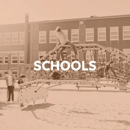 Children playing on playground equipment in front of a school building.