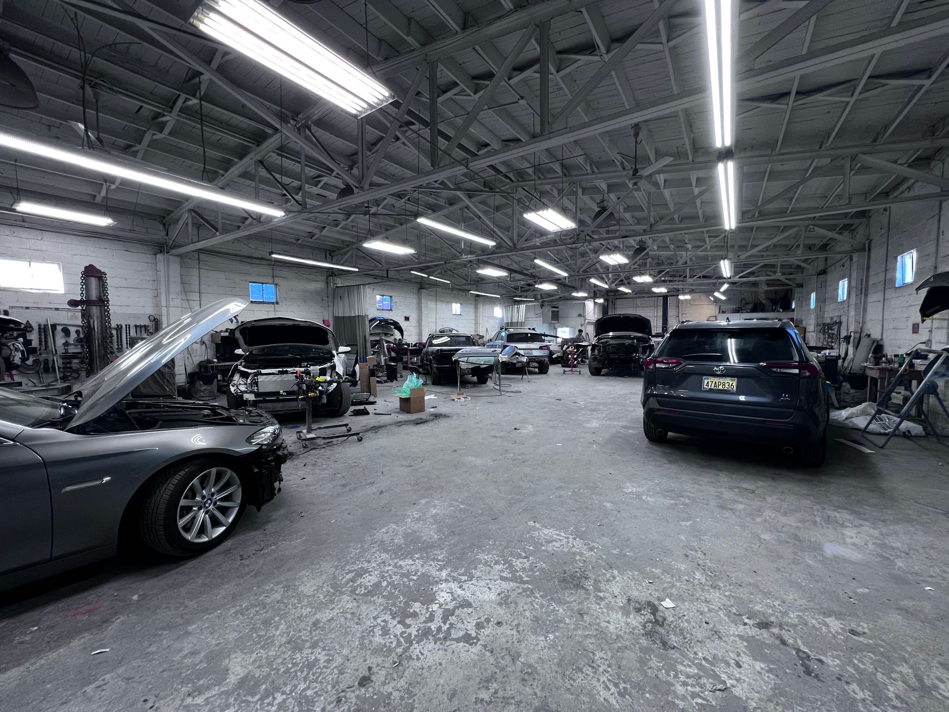 A black and white photo of a car repair shop filled with cars.