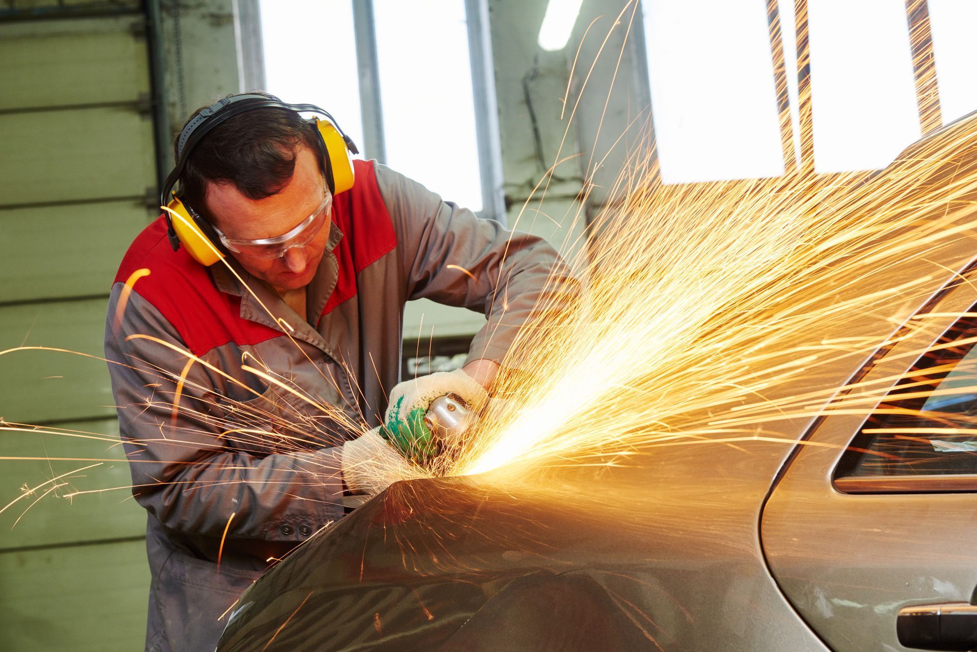 A man is grinding a car with a grinder in a garage.