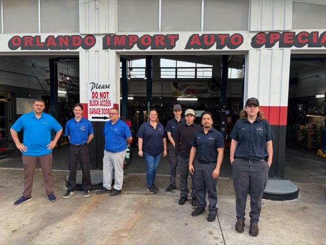 Group of eight people in front of an auto repair shop with the business name