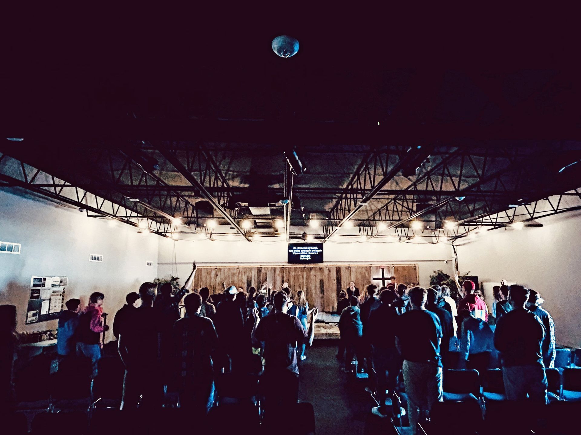 A large group of people are standing in a dark room.
