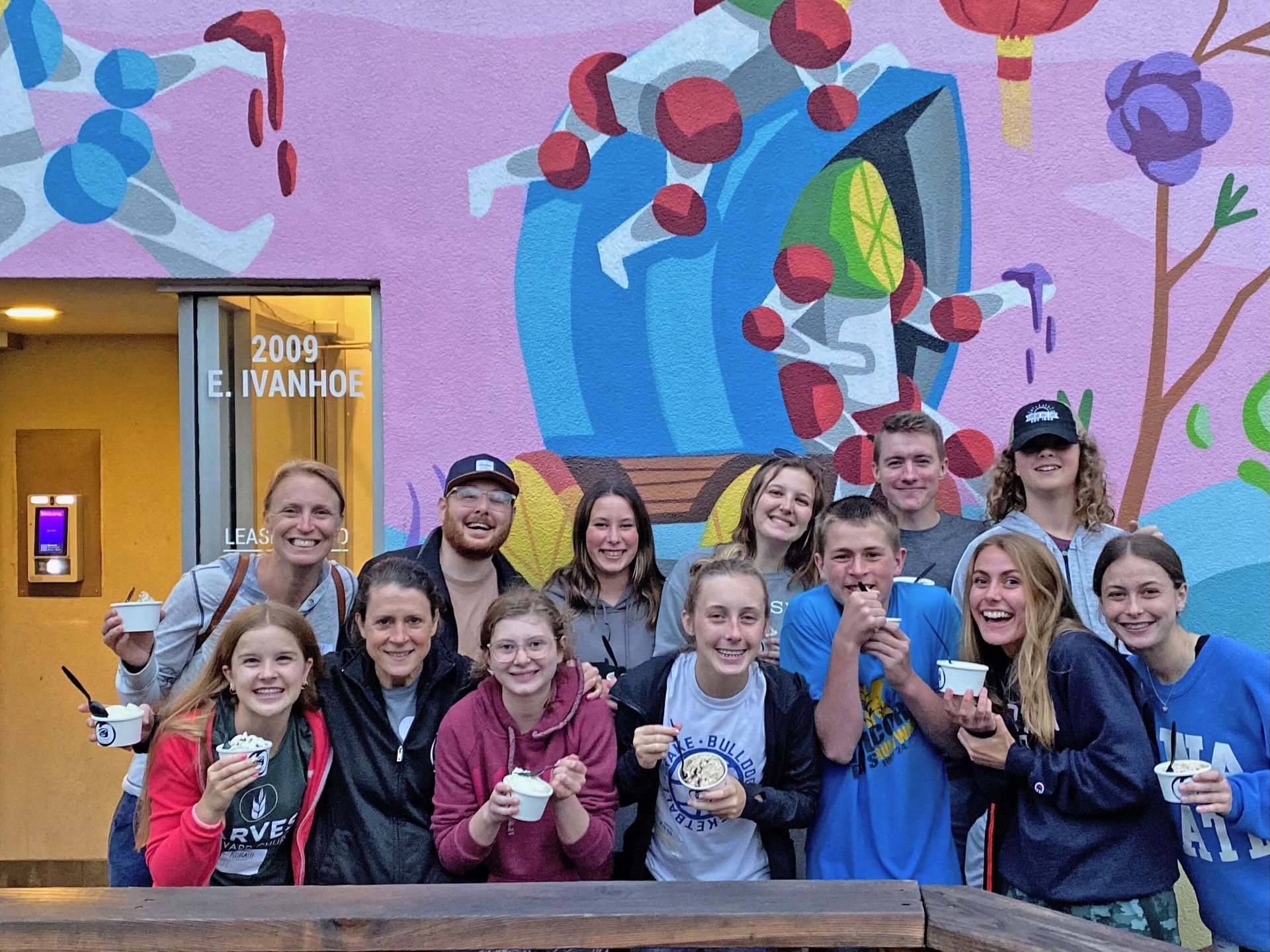 A group of people are posing for a picture in front of a mural.