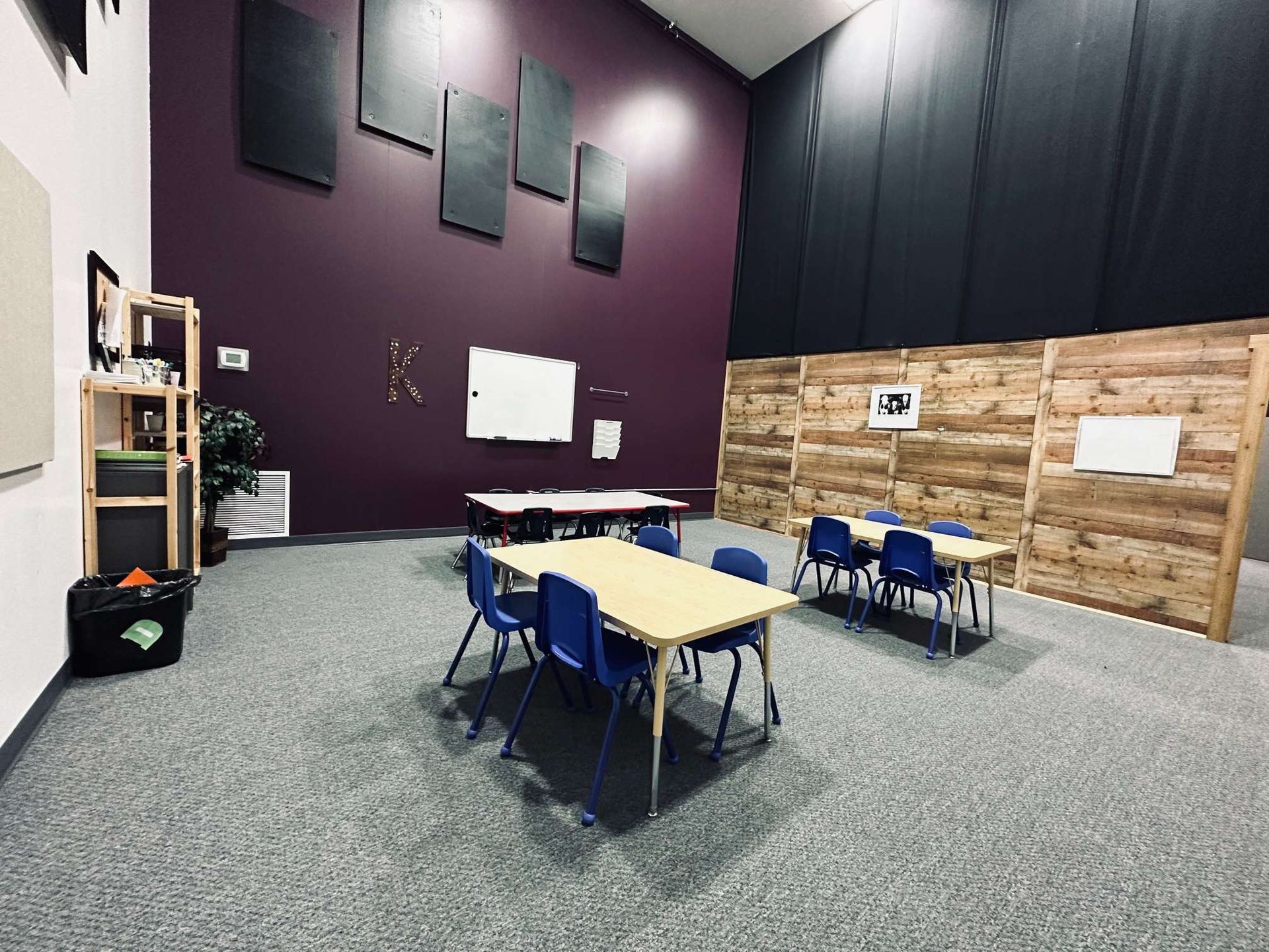 A room with tables and chairs and a wooden wall.
