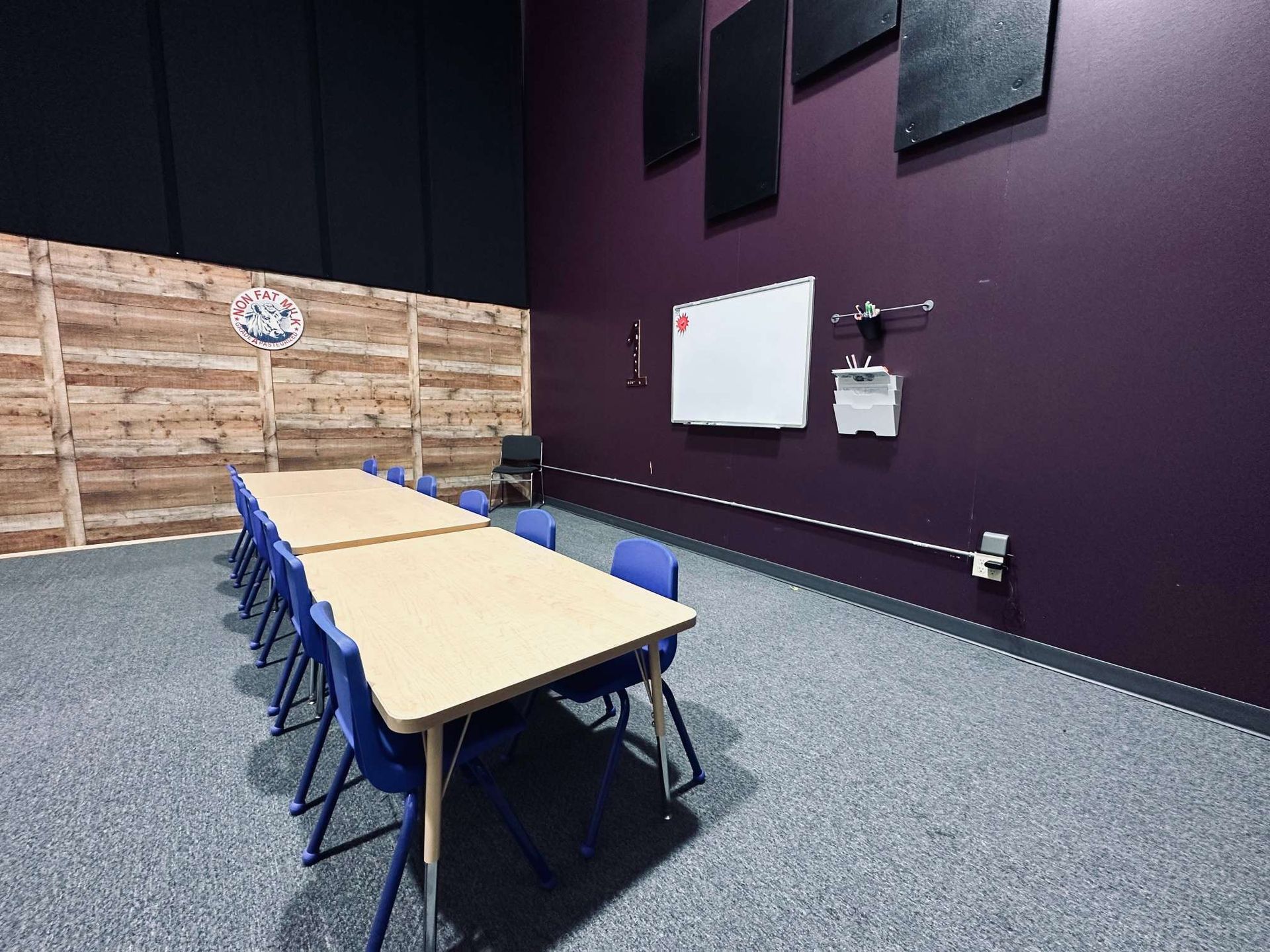A room with a long table and chairs and a whiteboard on the wall.