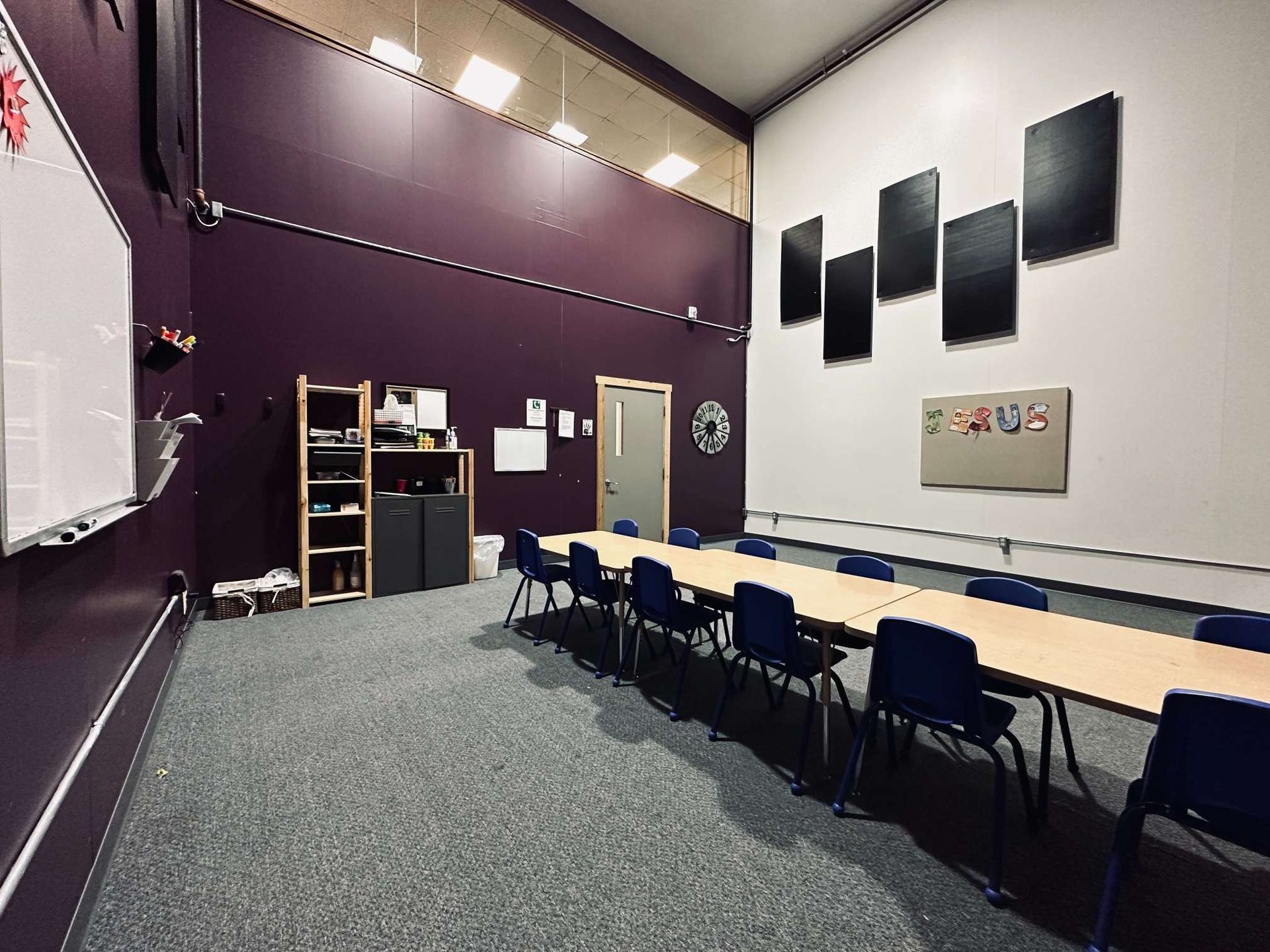 A classroom with a long table and chairs and a whiteboard.