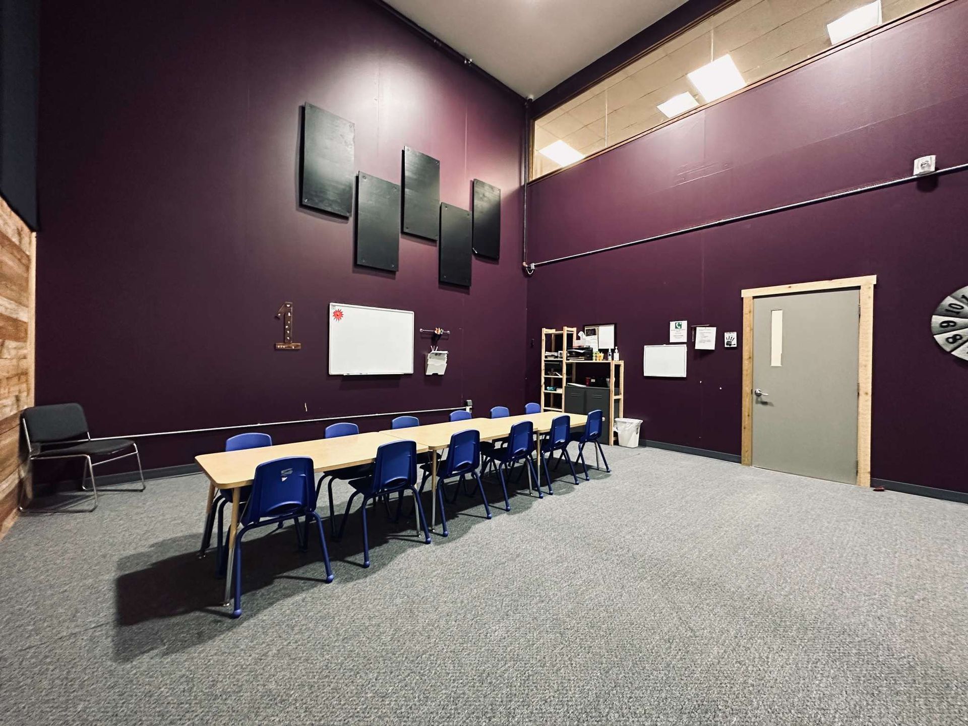 A large room with purple walls and a long table and chairs.