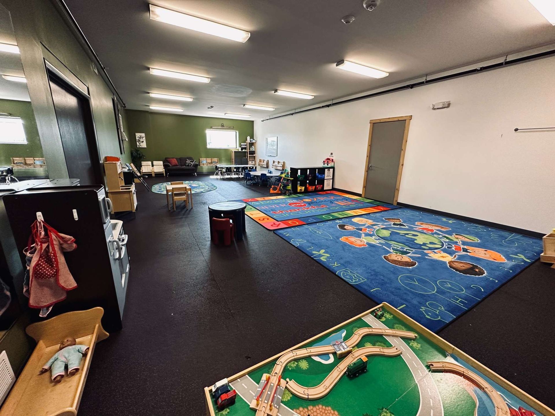 A large room filled with lots of toys and a train table.