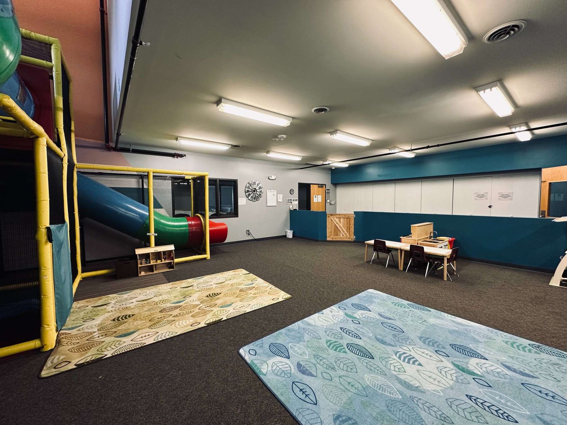 A large room with a slide , table and chairs in it.