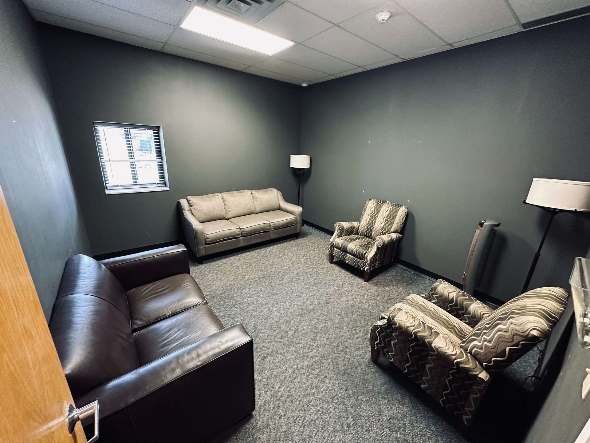 A living room with a couch and two chairs in it.