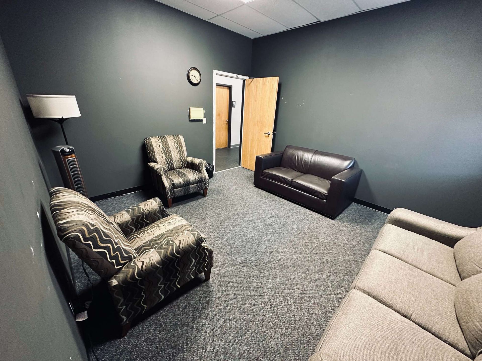 A living room with a couch , chairs and a lamp.