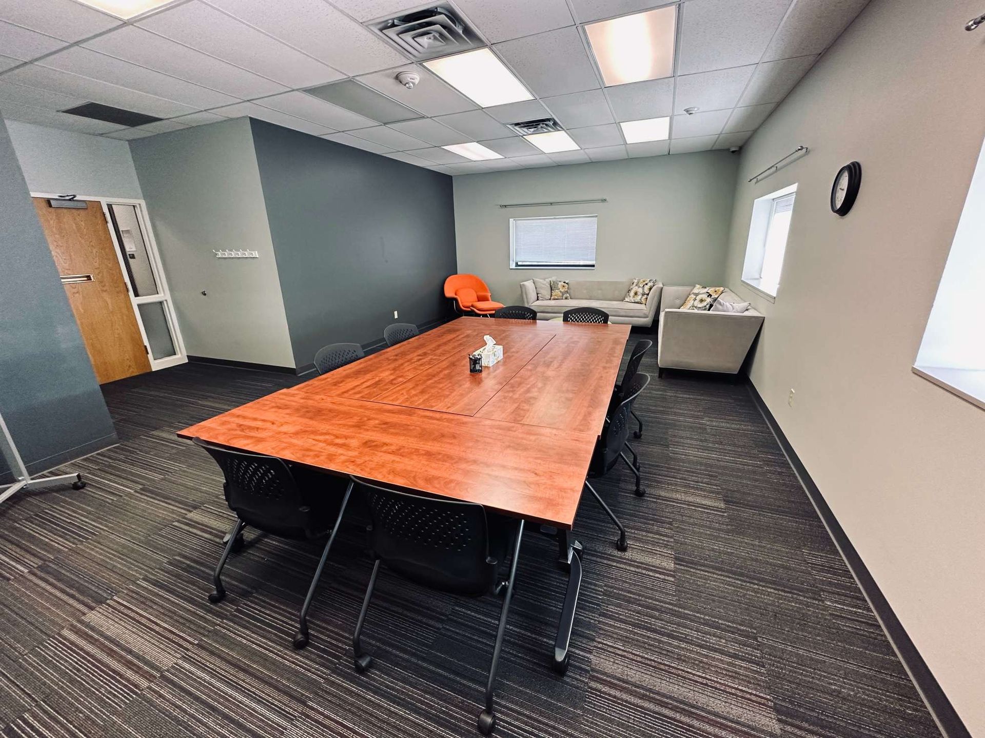 A conference room with a long wooden table and chairs.