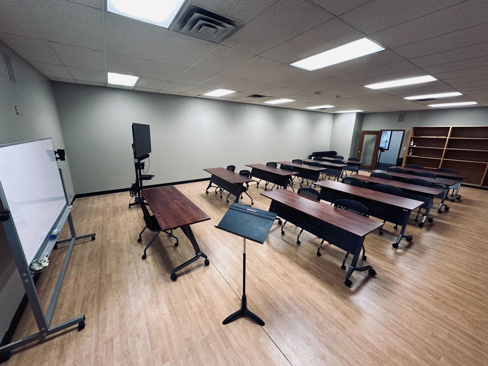 Empty classroom with tables, whiteboard, and music stand.
