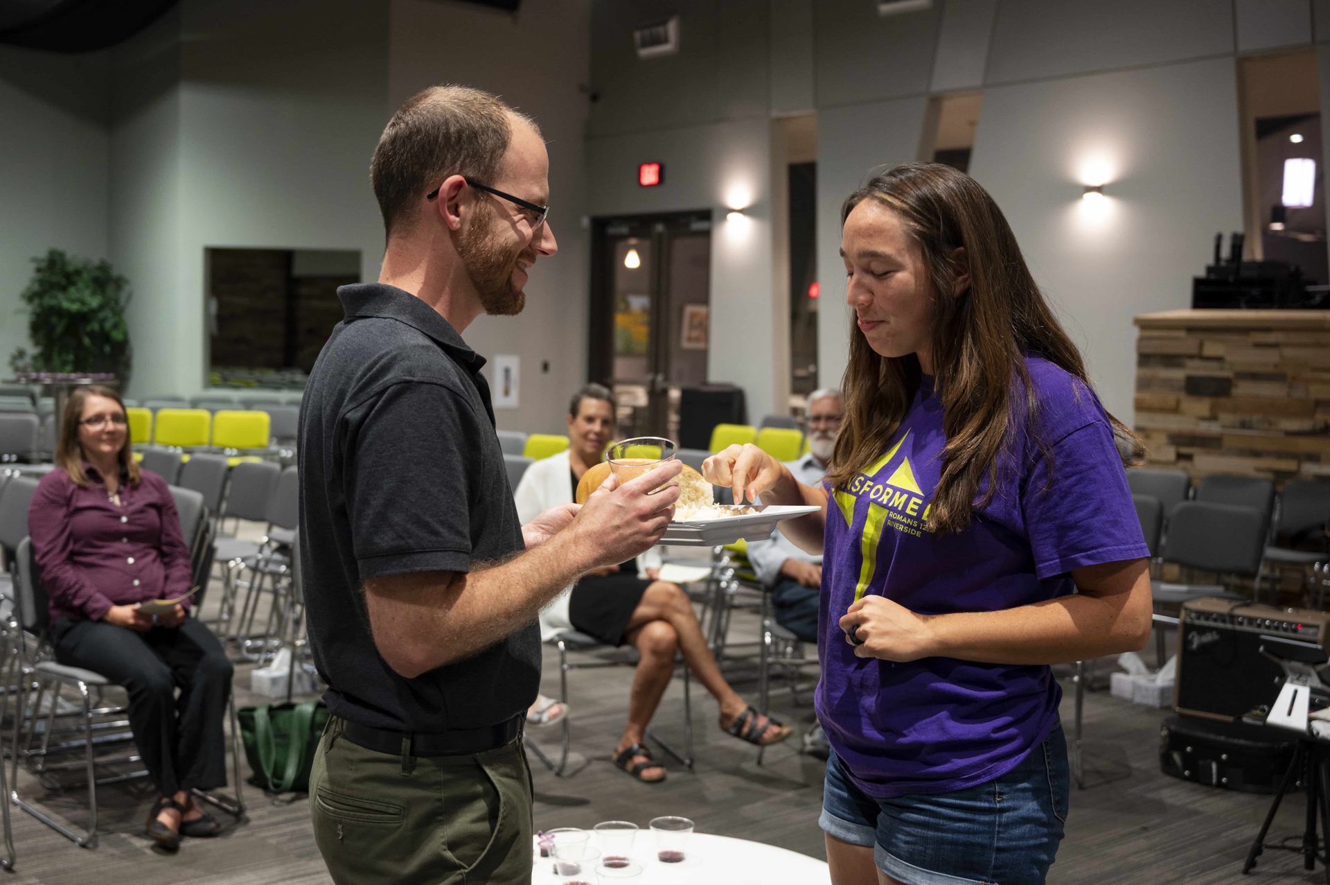 A man and a woman are standing next to each other in a room . the woman is wearing a purple shirt.