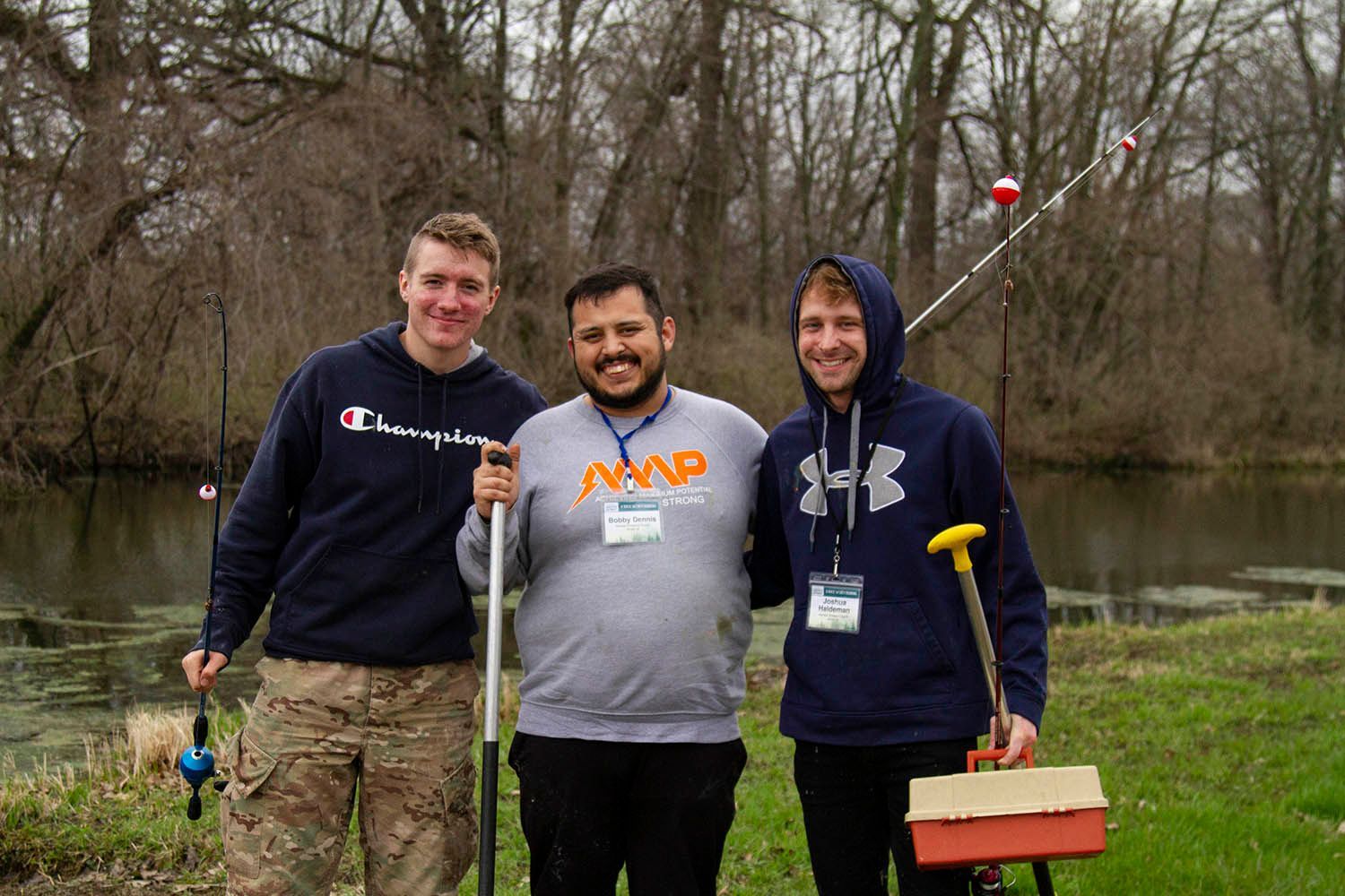 Three men are posing for a picture in front of a lake.