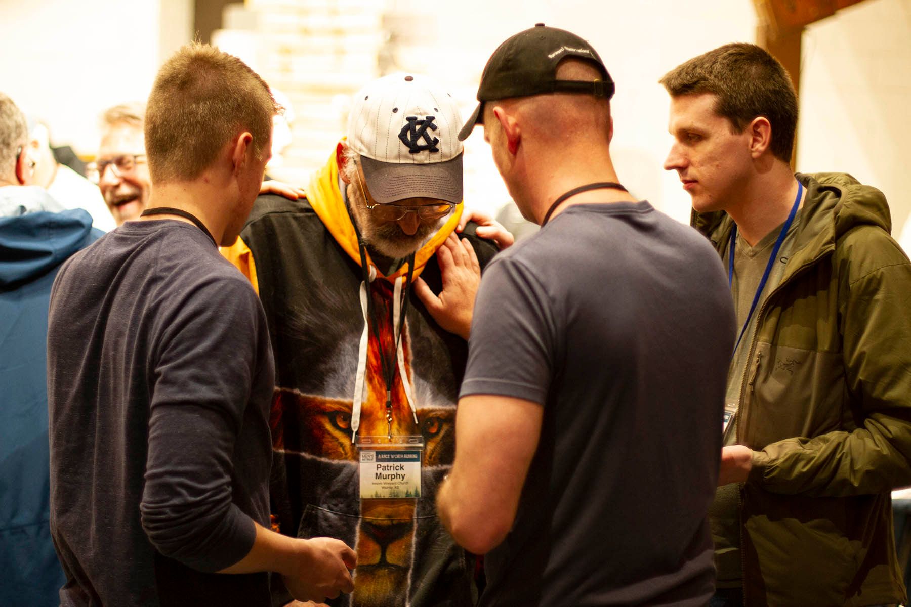 A group of men are standing around a man in a hoodie.