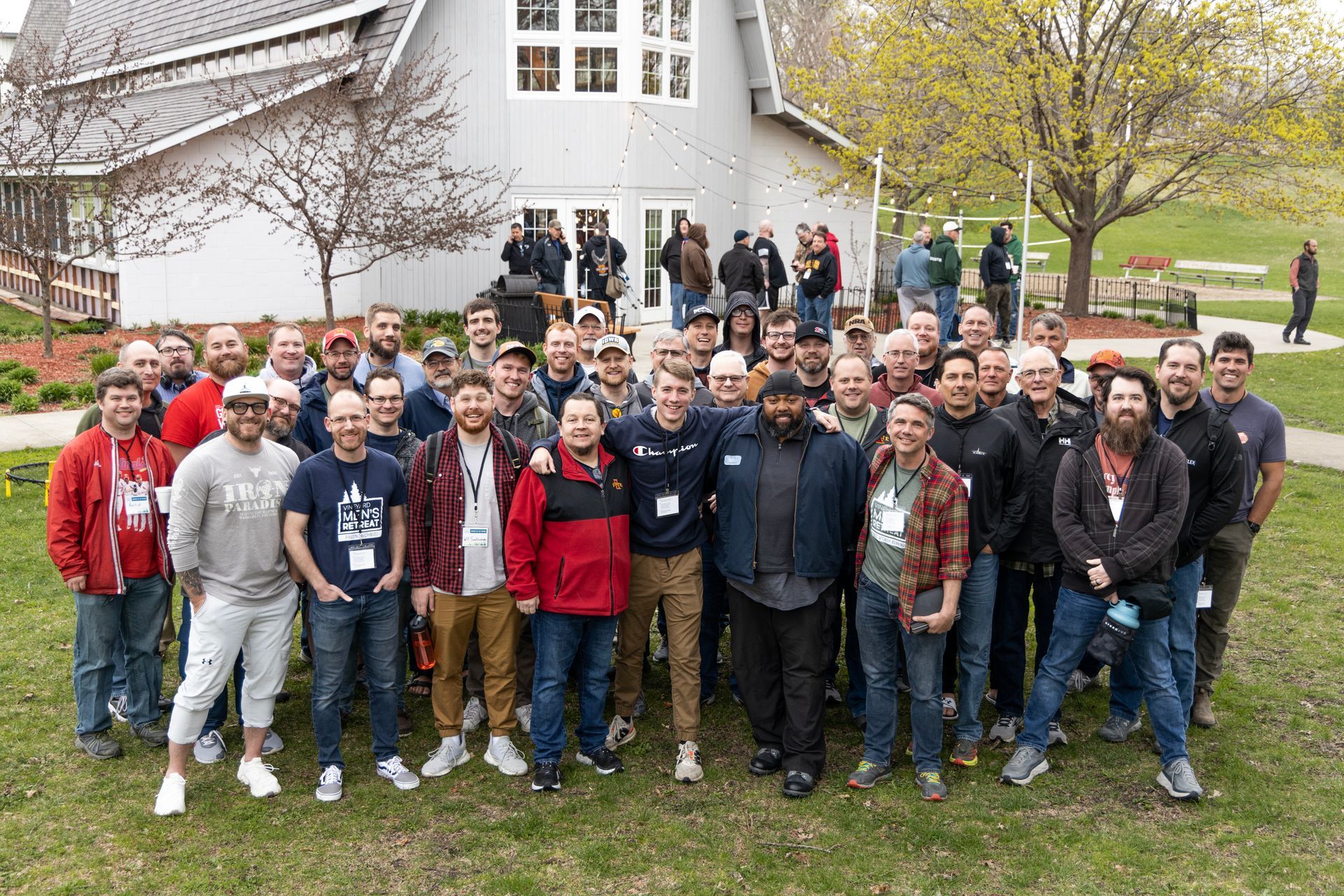 A large group of people are posing for a picture in front of a white barn.