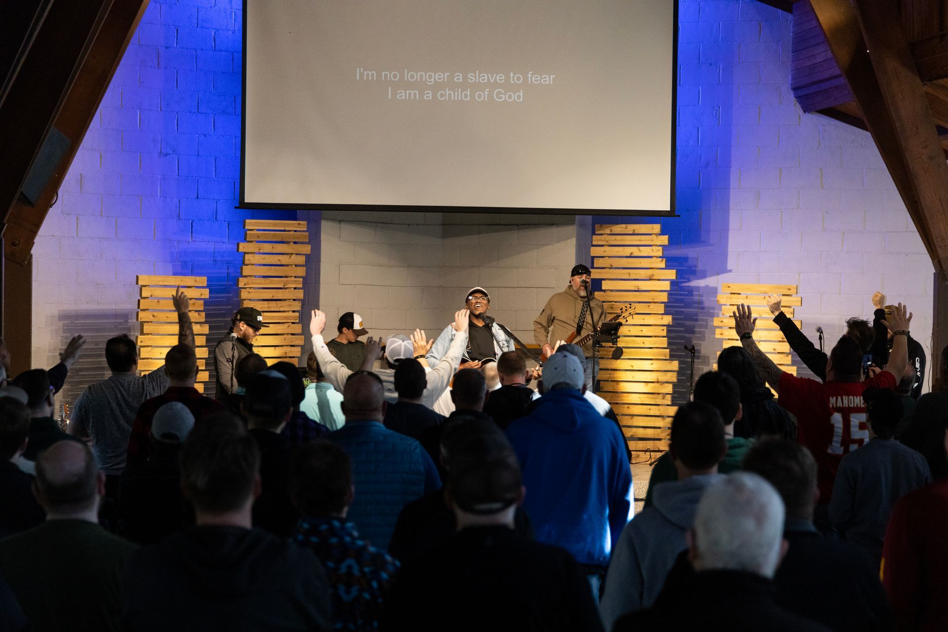 A large group of people are standing in front of a large screen in a church.