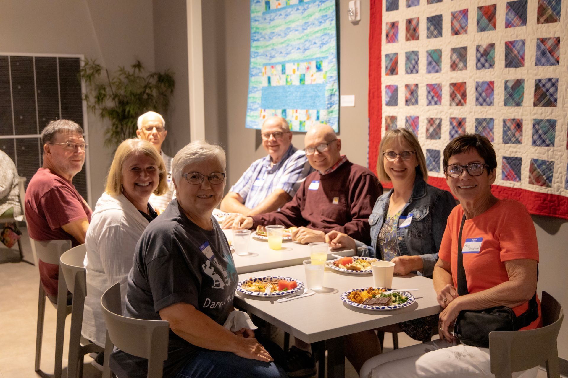 A group of people are sitting around a table with plates of food.