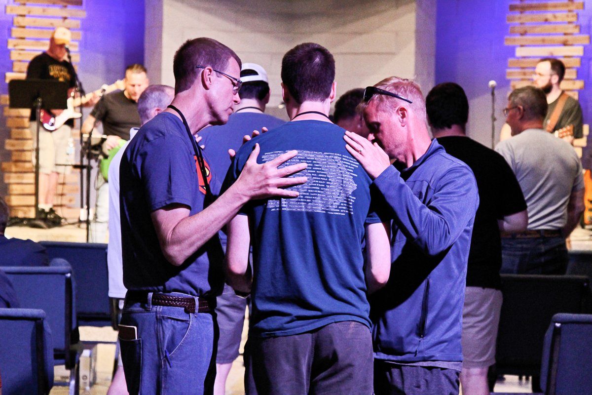 A group of men are praying together in a church.