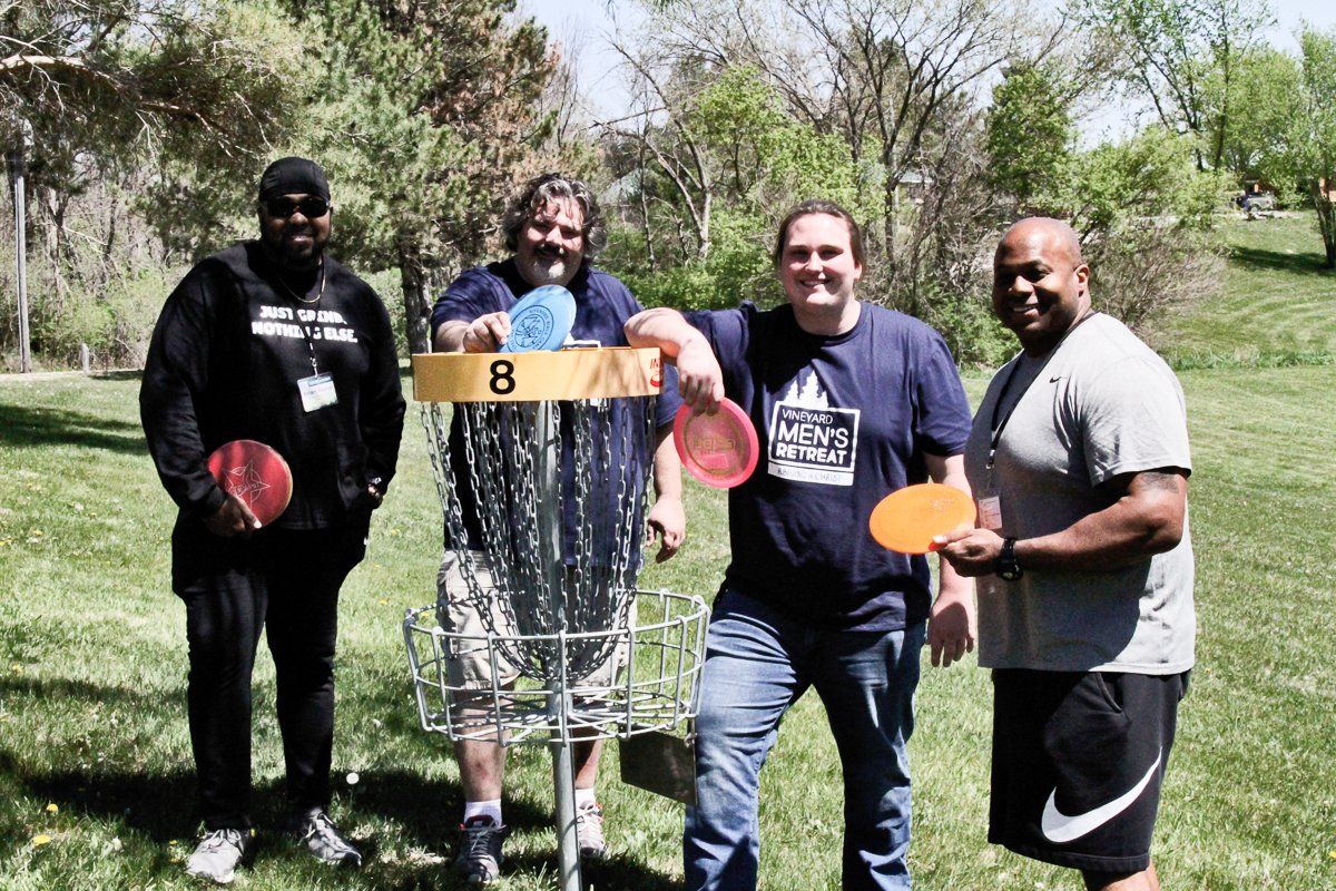 A group of people are standing in front of a frisbee golf basket with the number 8 on it.