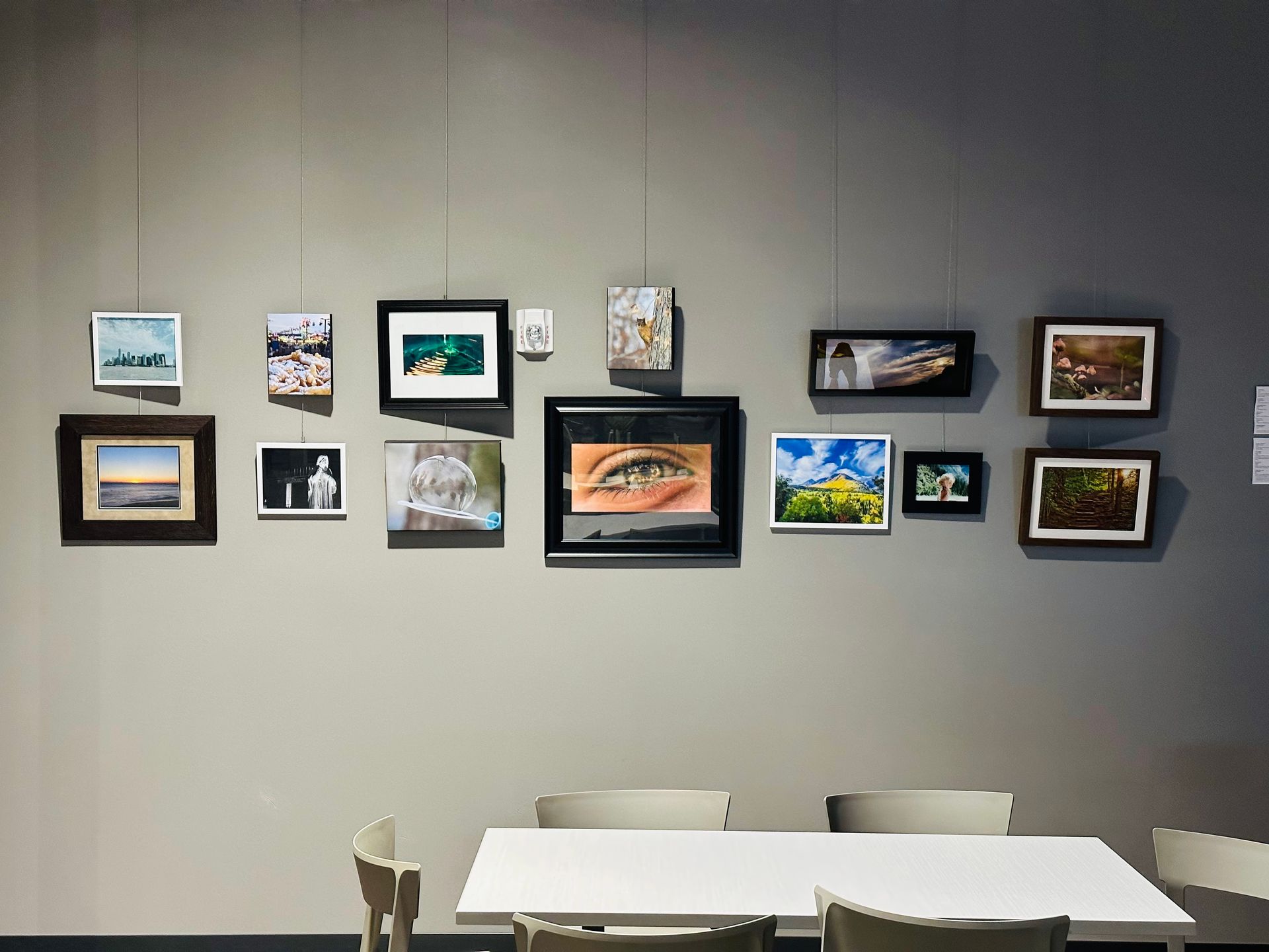 A table and chairs in front of a wall with paintings on it