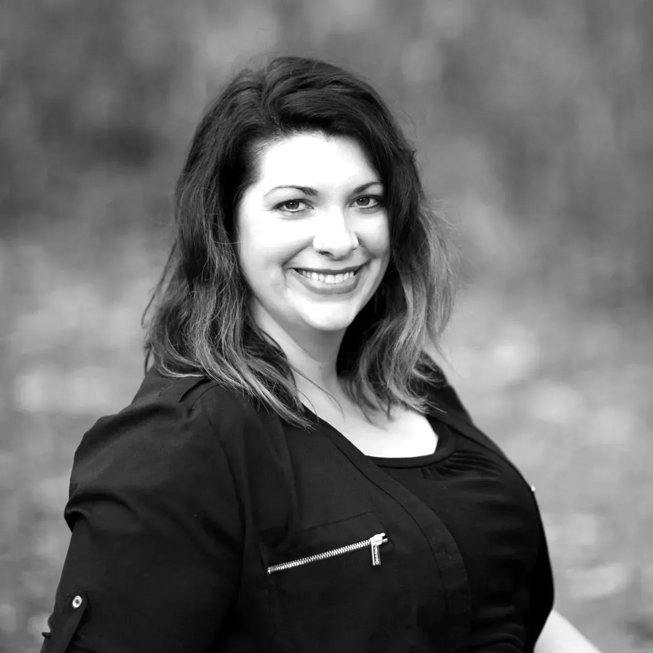 A black and white photo of a smiling woman in a black jacket.