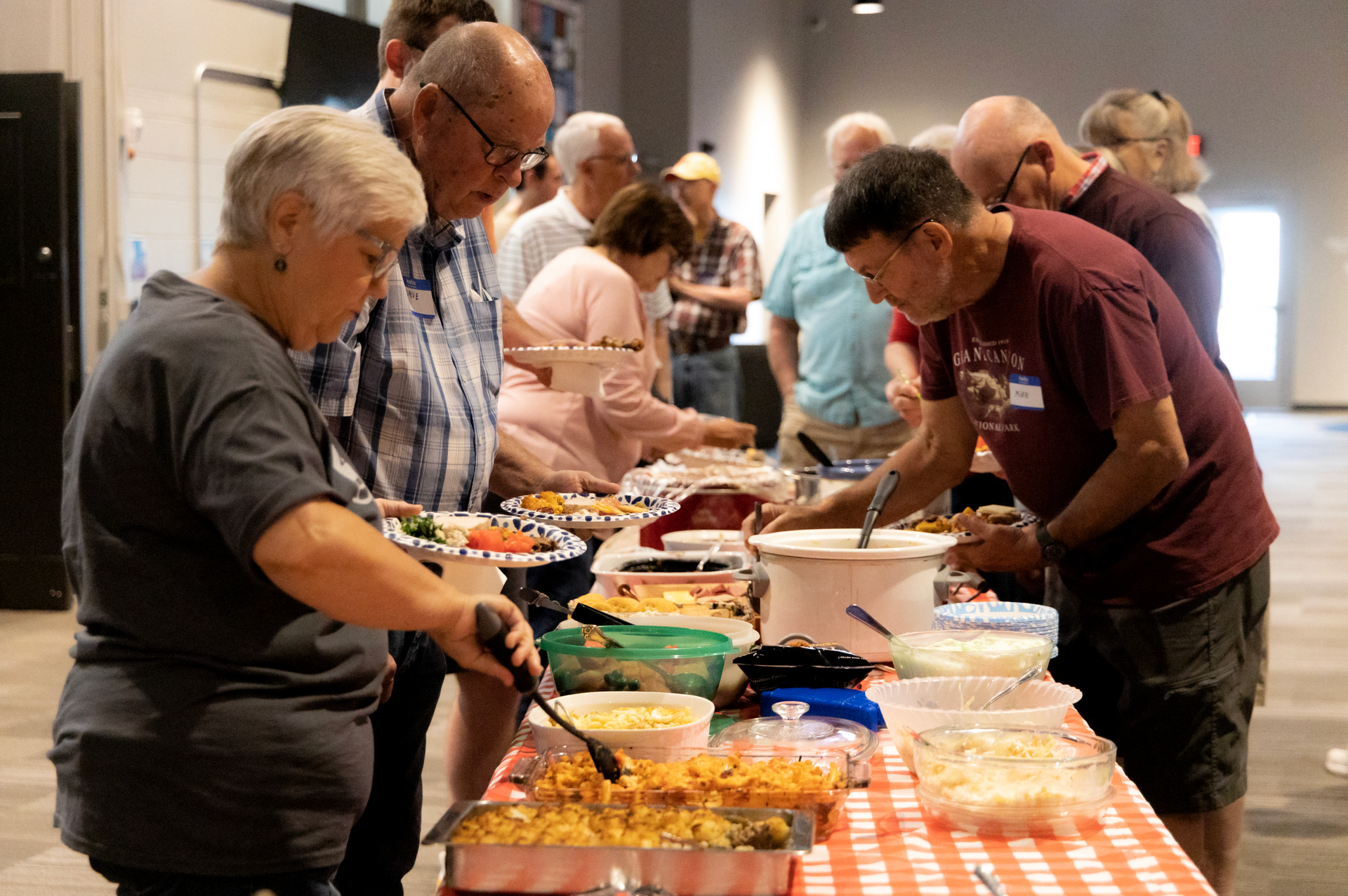 A group of people are standing around a table eating food.