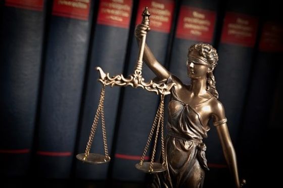 A statue of lady justice standing in front of a row of books