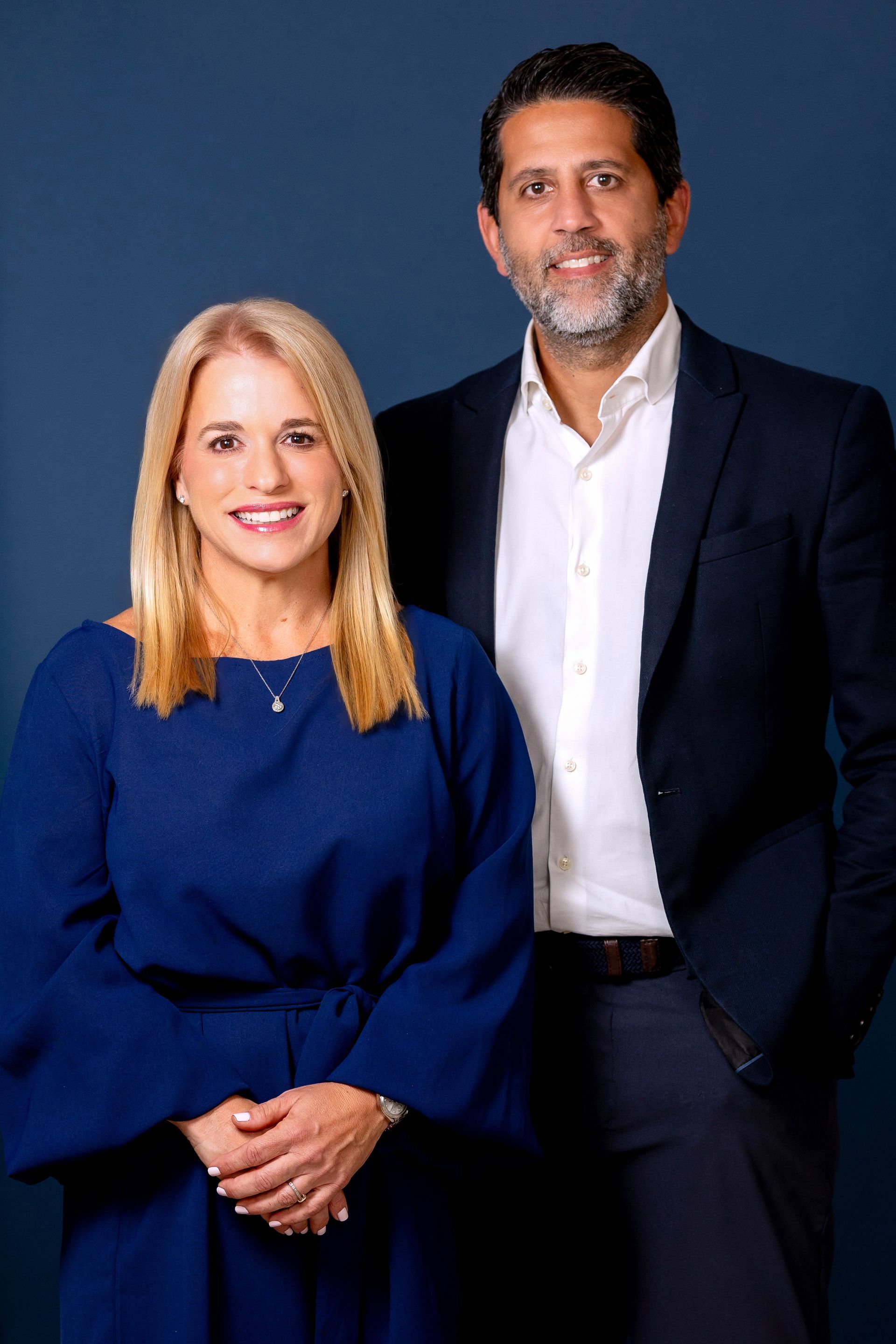 Josean and Marie posing against a blue backdrop
