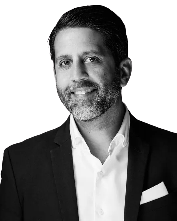 Josean wearing a black blazer and white shirt, smiling, with a pocket square.