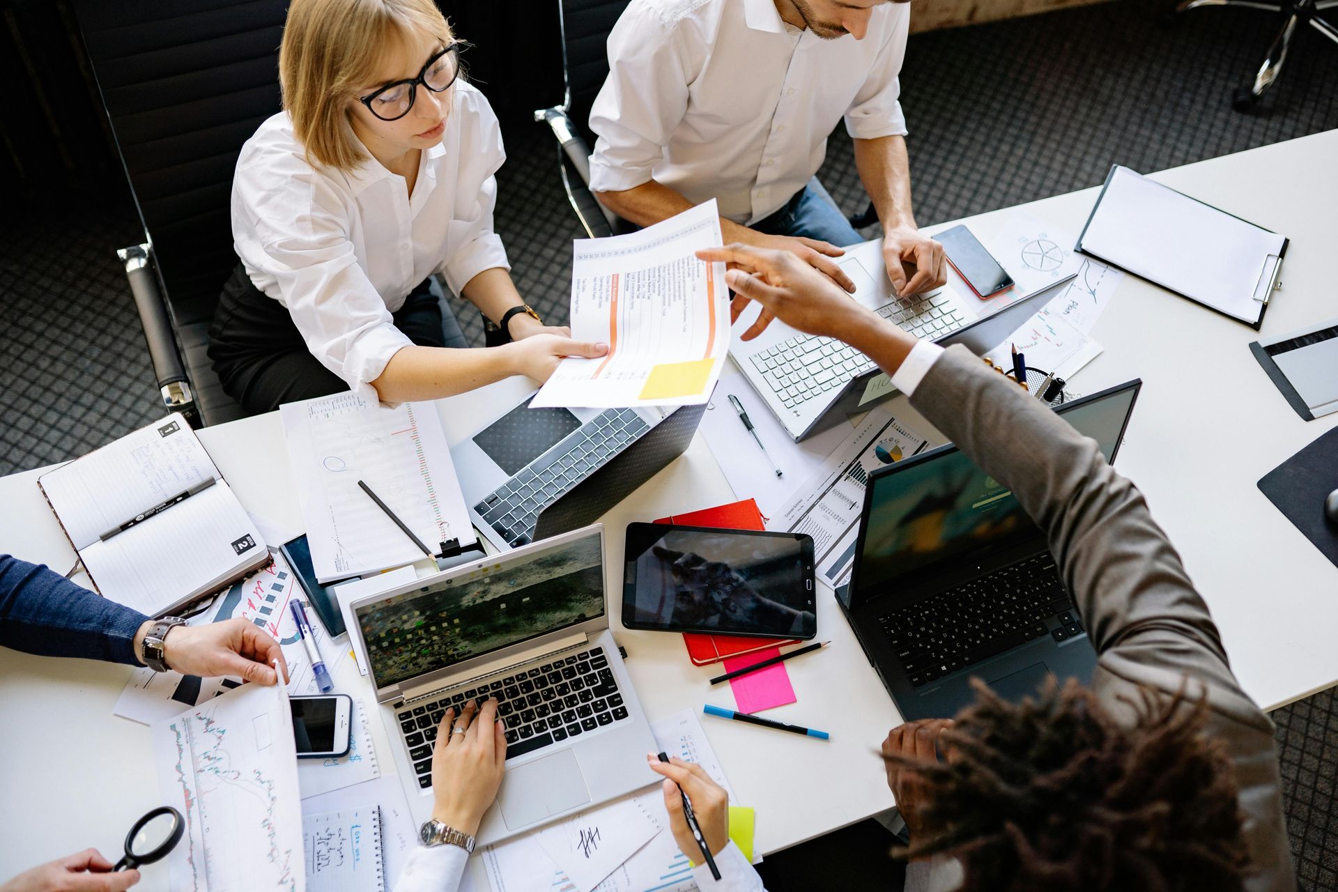 Team collaborating around laptops and documents at a conference table in a bright office