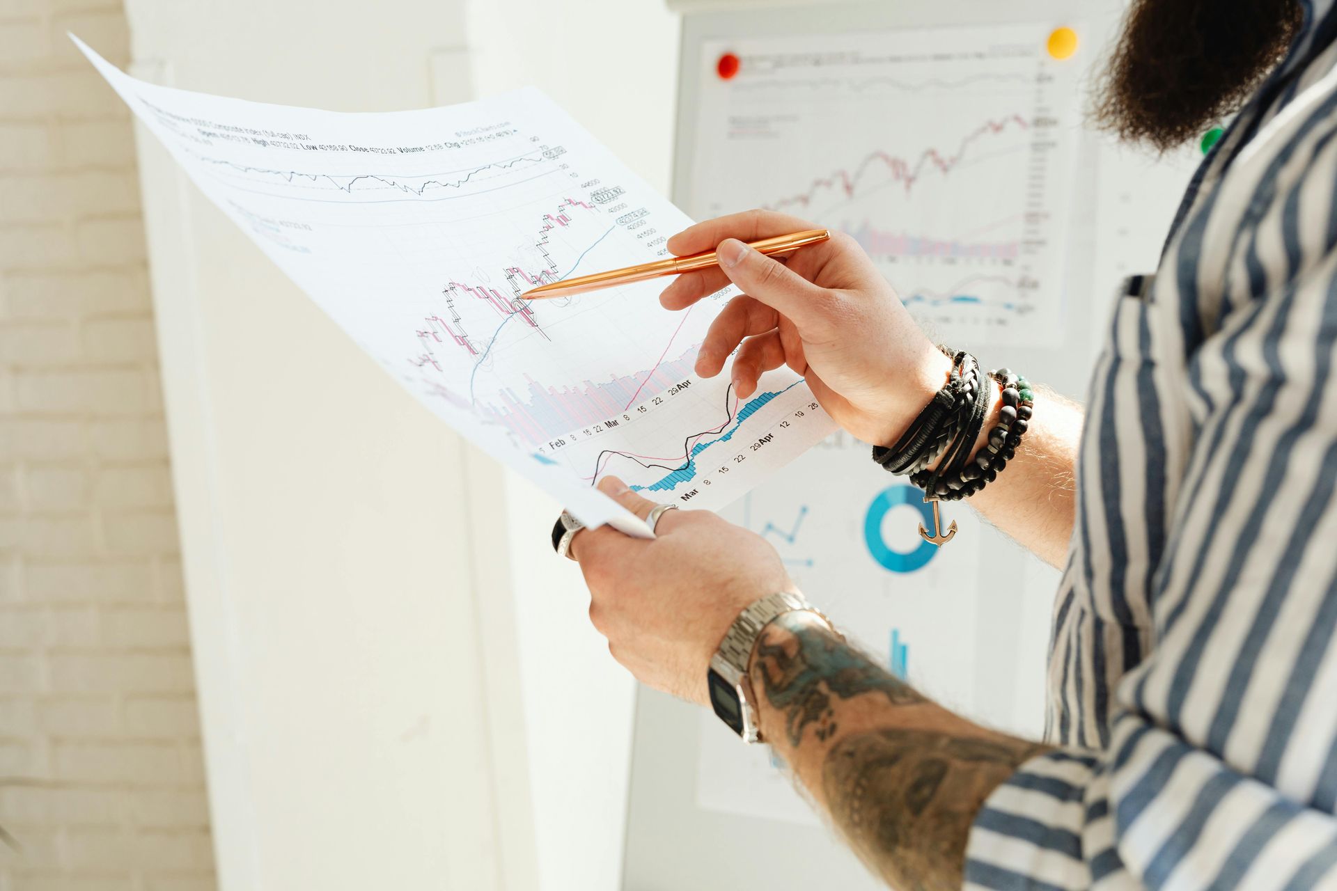 Hands pointing at colorful charts on a wall in a bright office setting