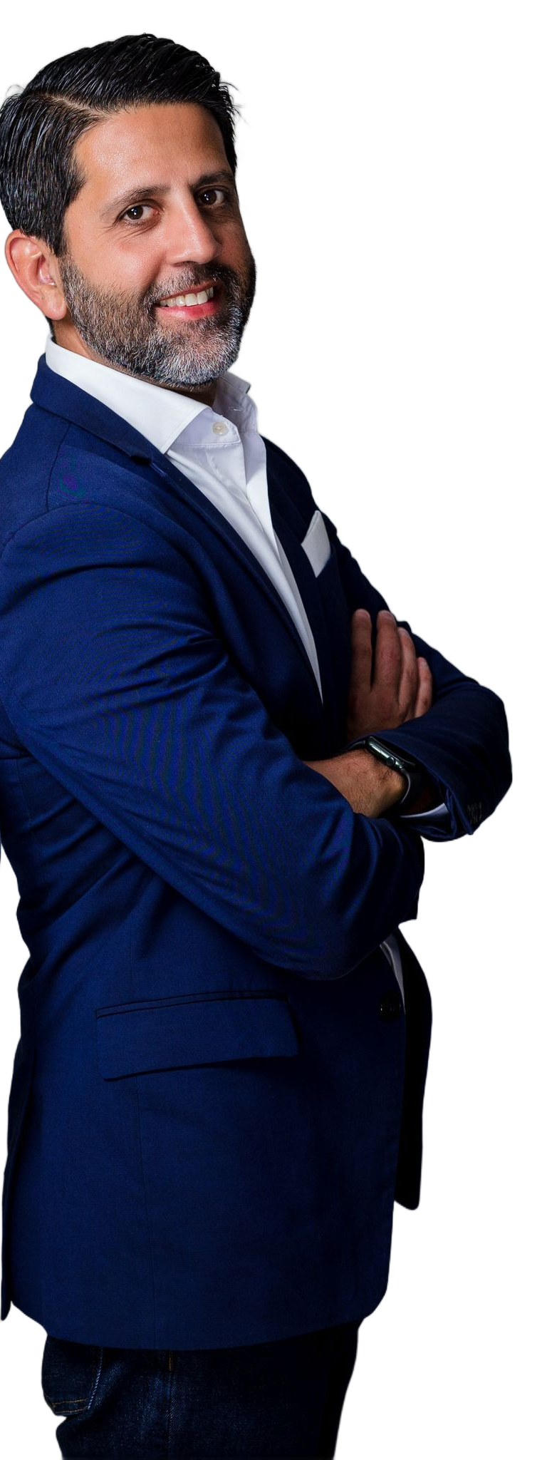 A man with a beard, wearing a blue blazer and white dress shirt, stands with his arms crossed against a white background.