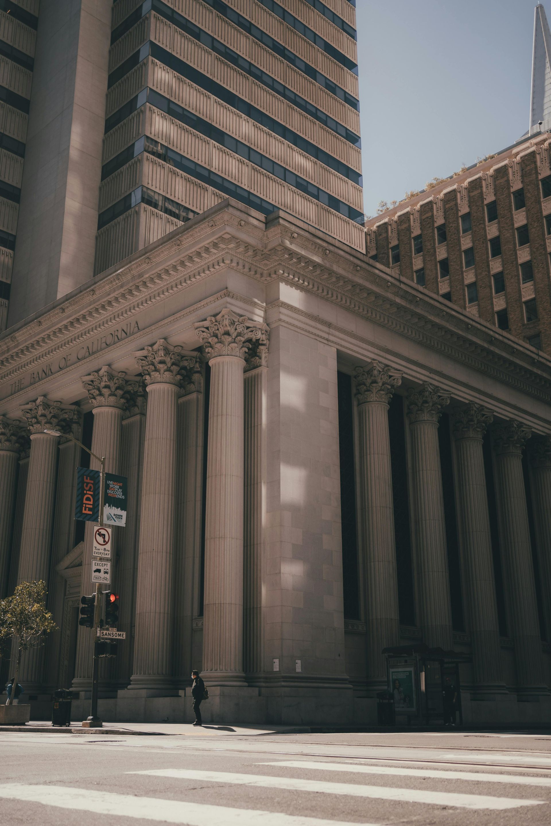 A neoclassical building with tall columns in a city setting, with a pedestrian crossing.