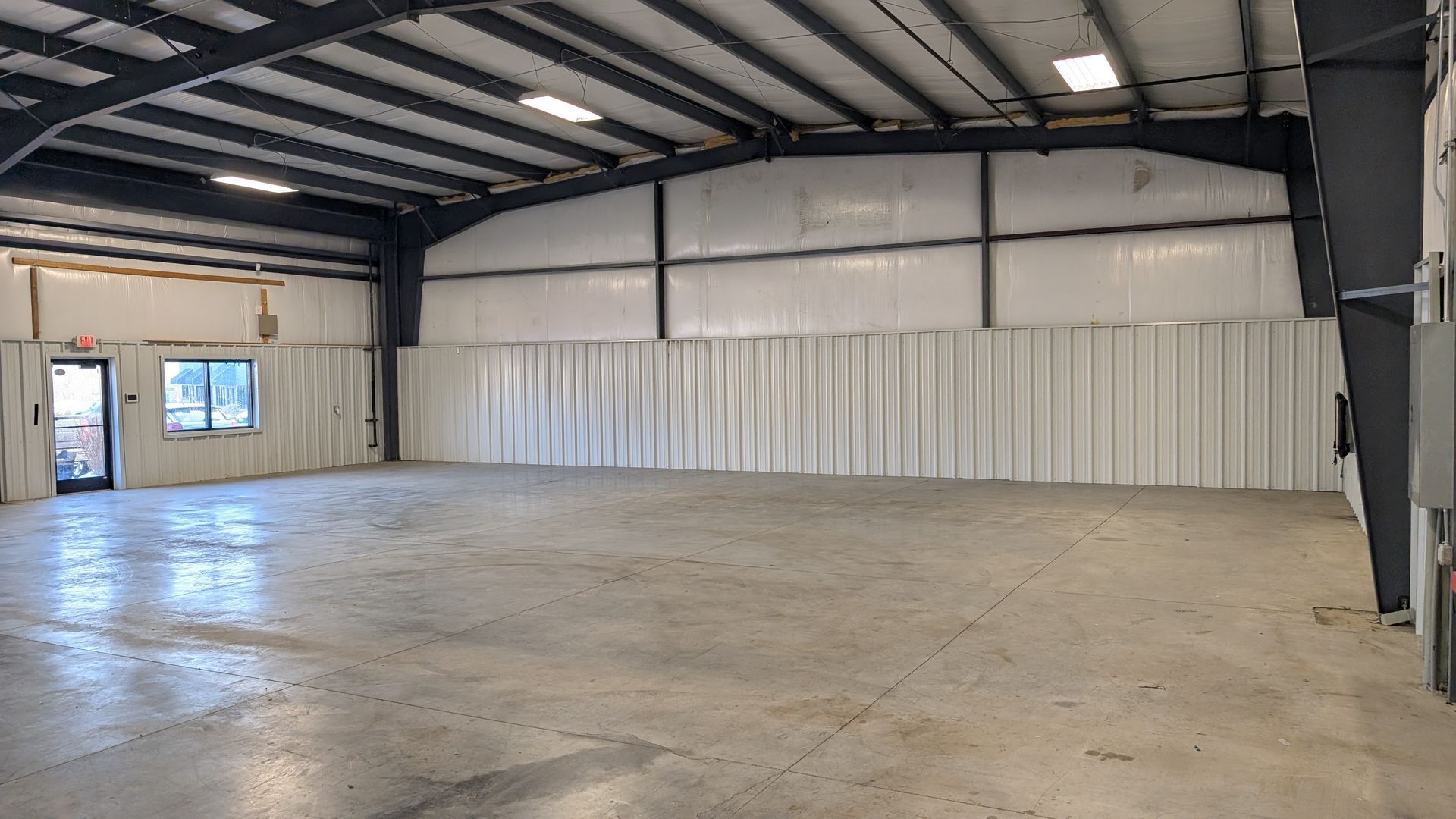 Spacious warehouse interior with stacked boxes, equipment, and a concrete floor under exposed beams.