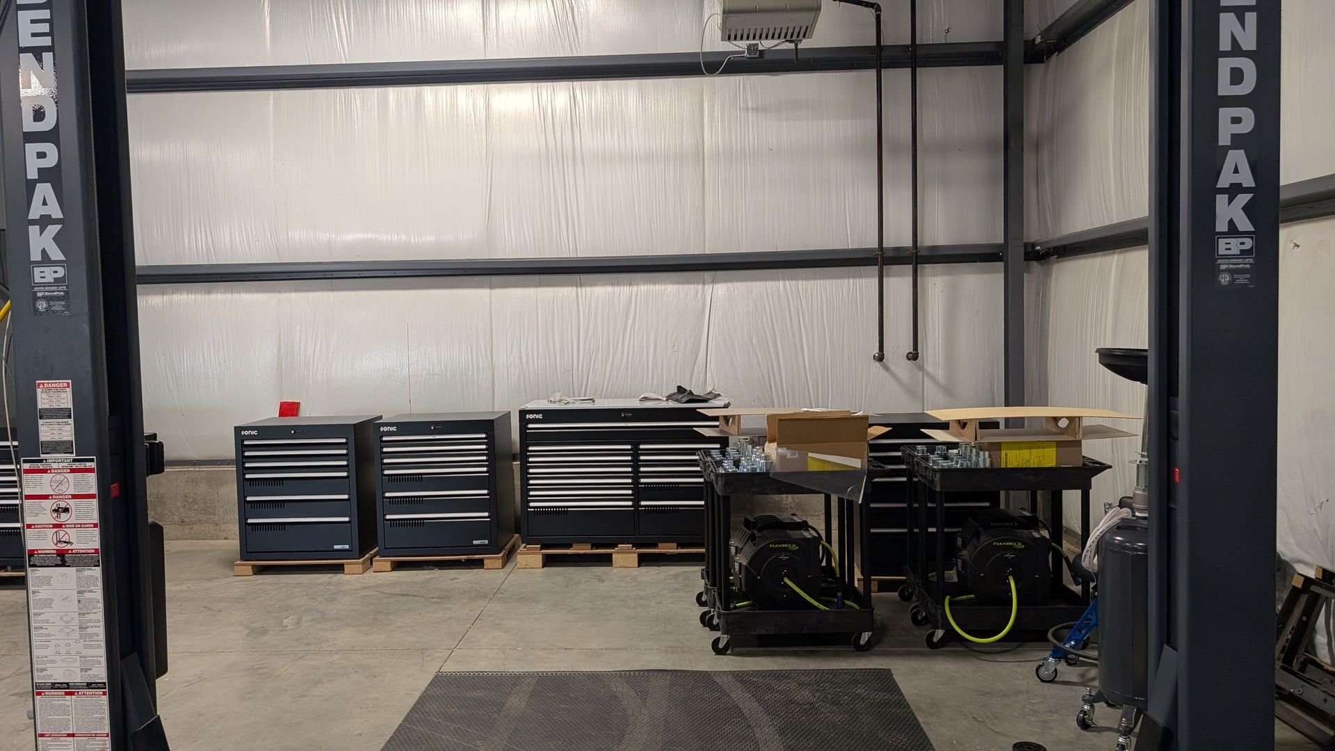 Auto repair shop with car lift, tool chests, and equipment against a metal wall