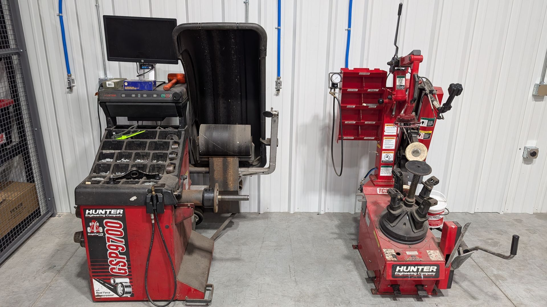 Indoor workshop with red equipment, tools, and machinery lined along a metal-walled garage.