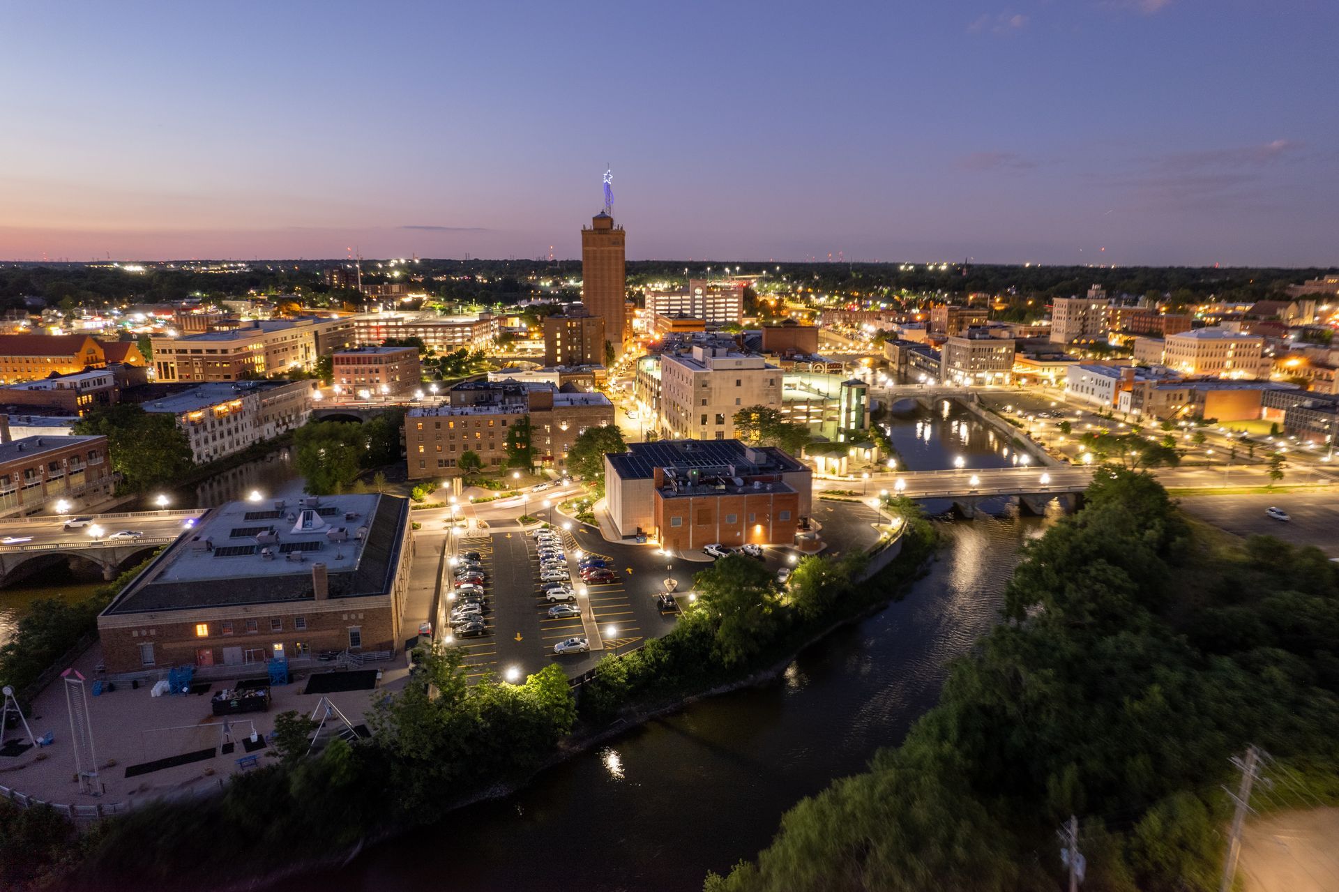 An aerial view of a city at night with a river in the foreground.