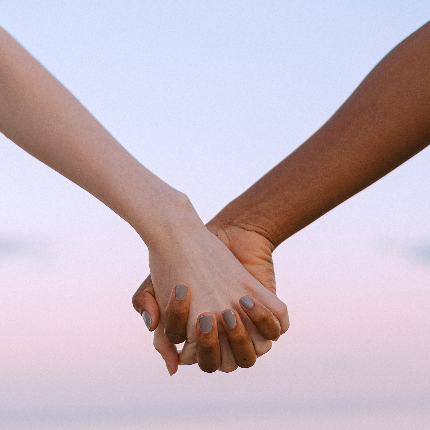 Two people holding hands with one being white and the other black