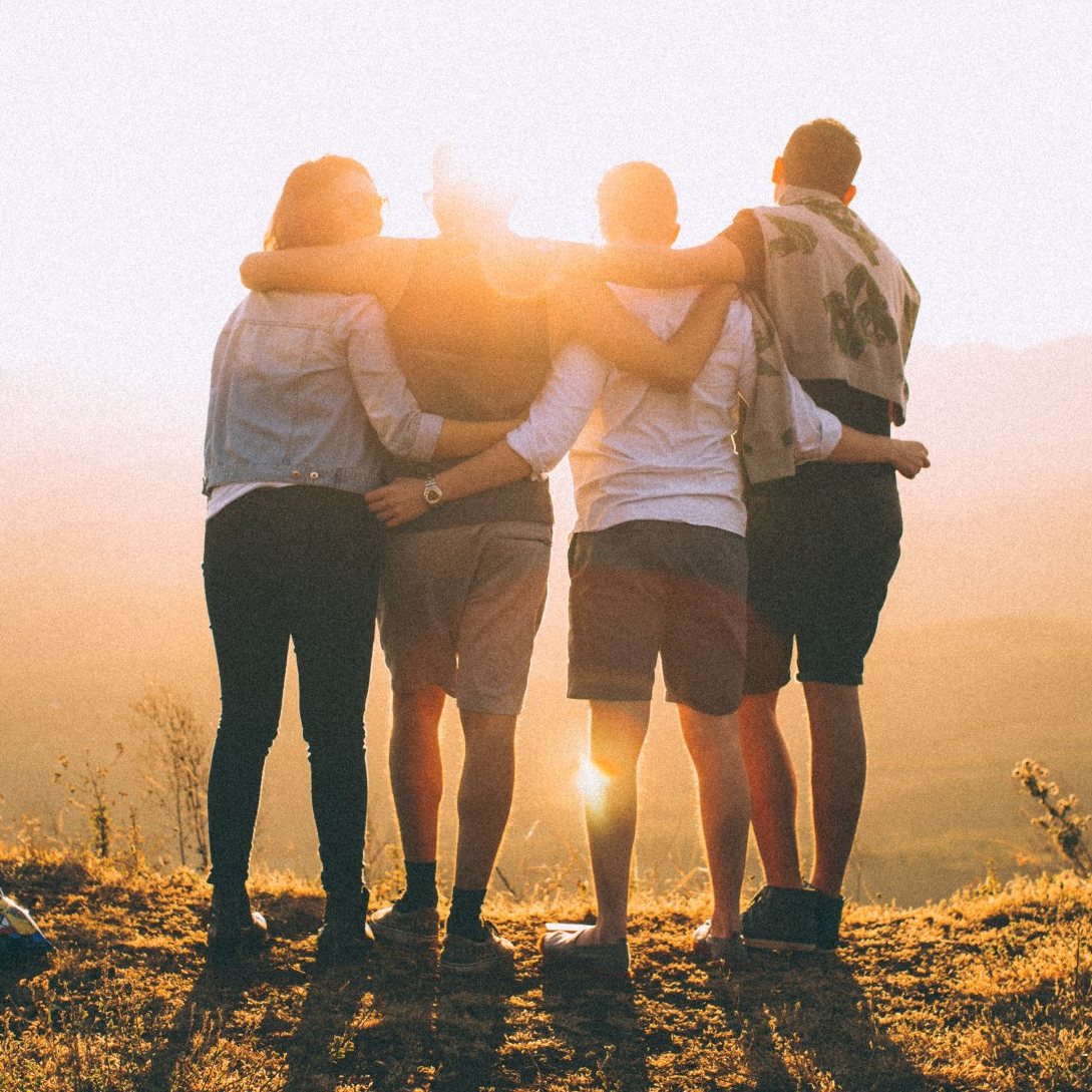 A group of people are hugging each other on top of a hill.