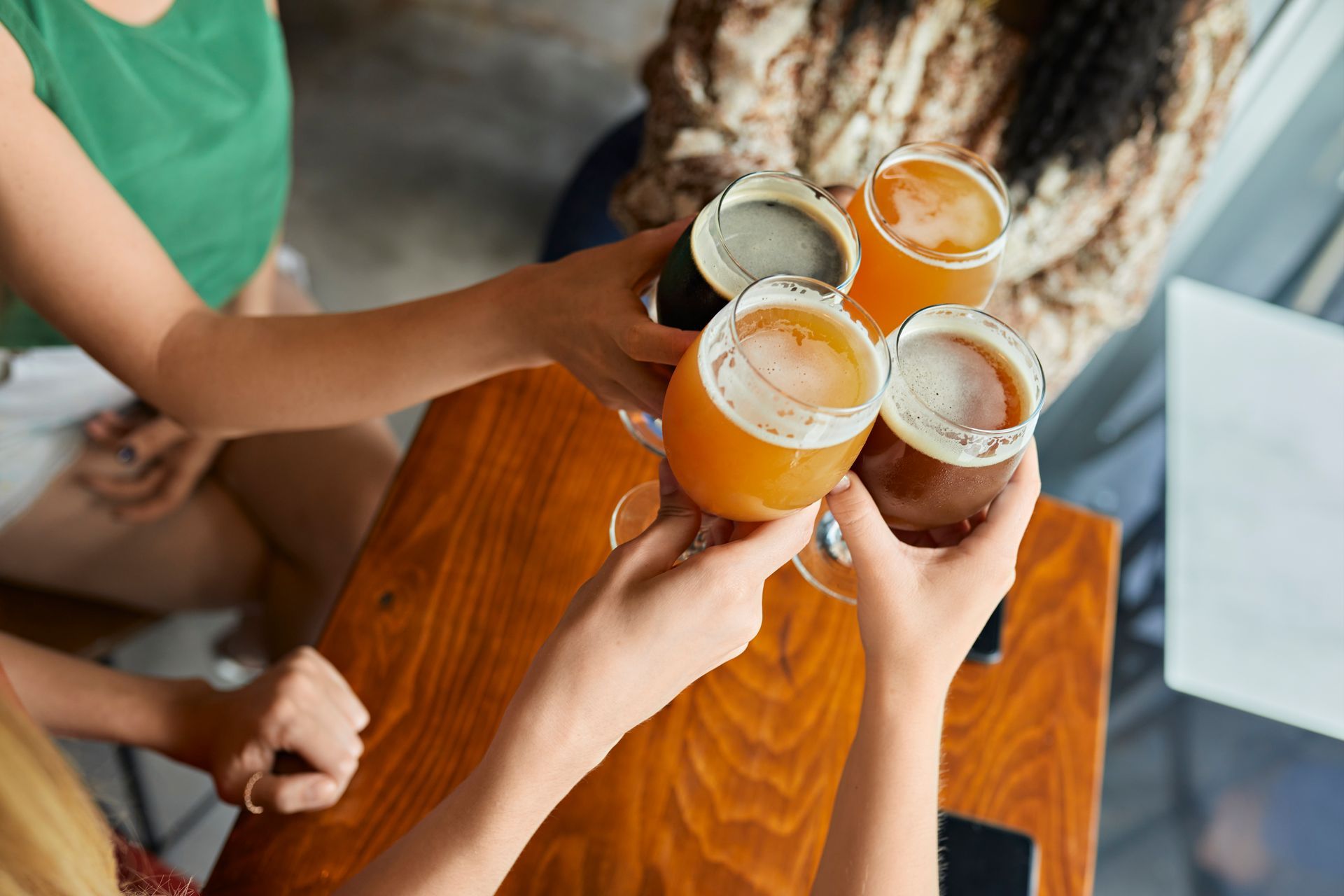 Un gruppo di persone sta brindando con bicchieri di birra seduti a un tavolo.