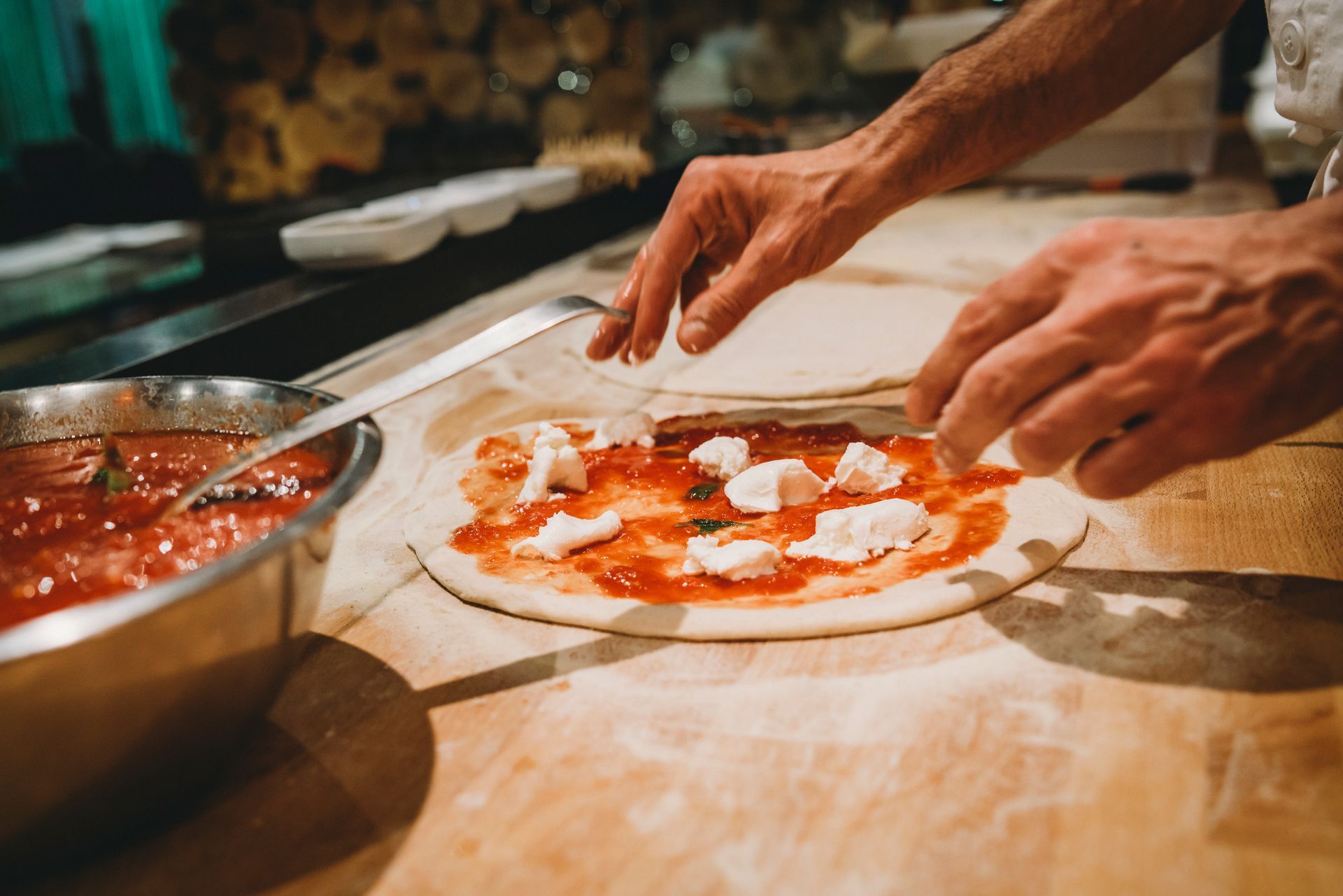 Una persona sta preparando una pizza su un tavolo di legno.