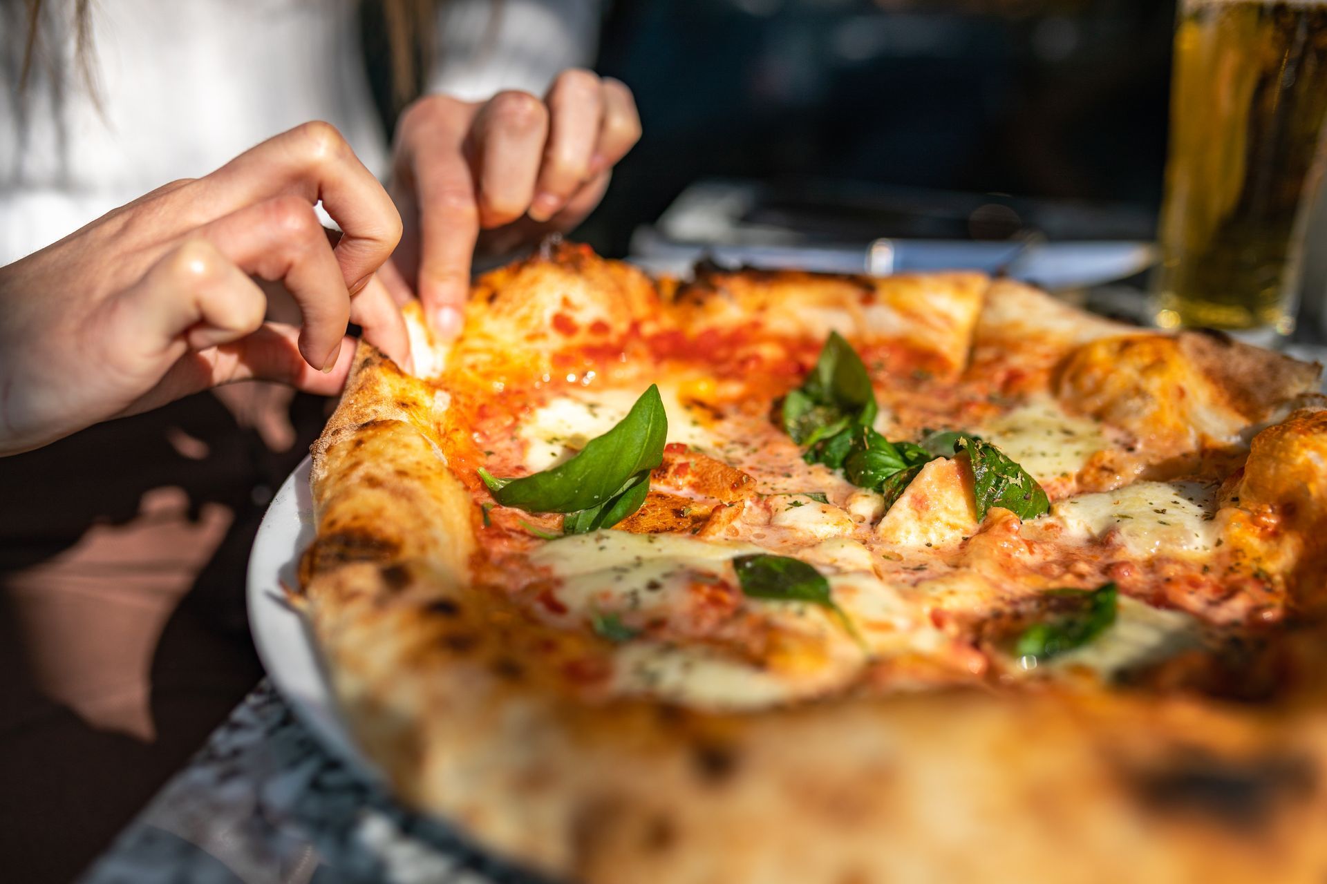 Una persona sta prendendo una fetta di pizza da un piatto.
