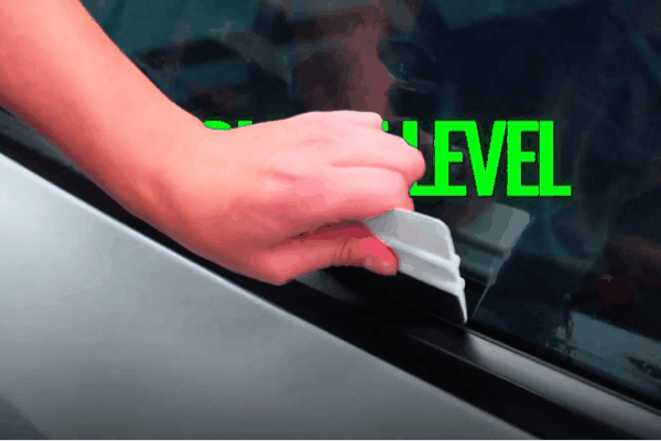 Technician applying window tint film to a vehicle side window at Auto Envy