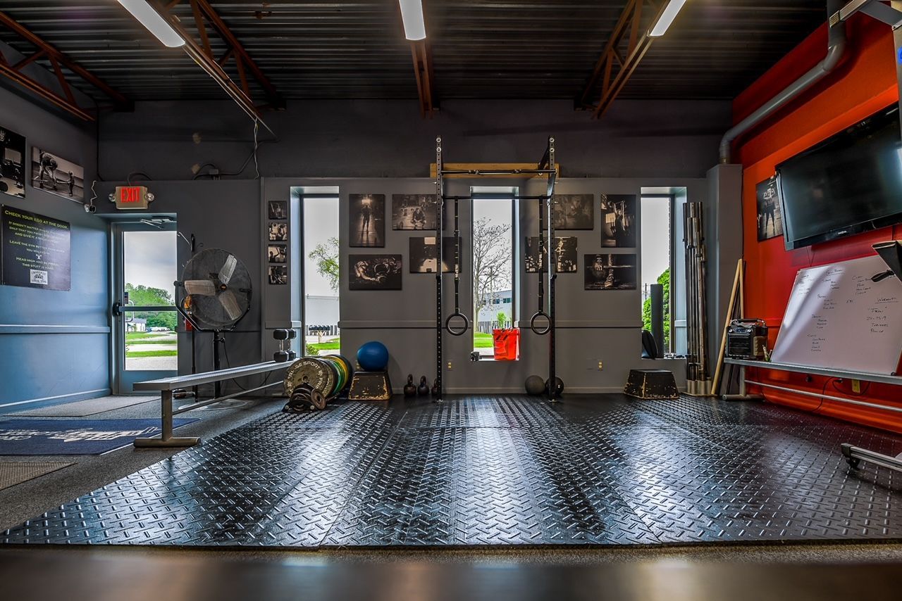 A gym with a lot of exercise equipment and a tv on the wall.