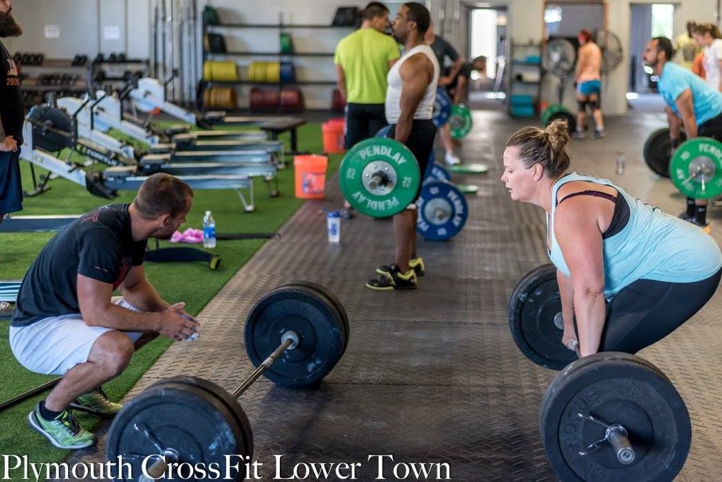 A group of people are lifting weights in a gym in plymouth crossfit lower town