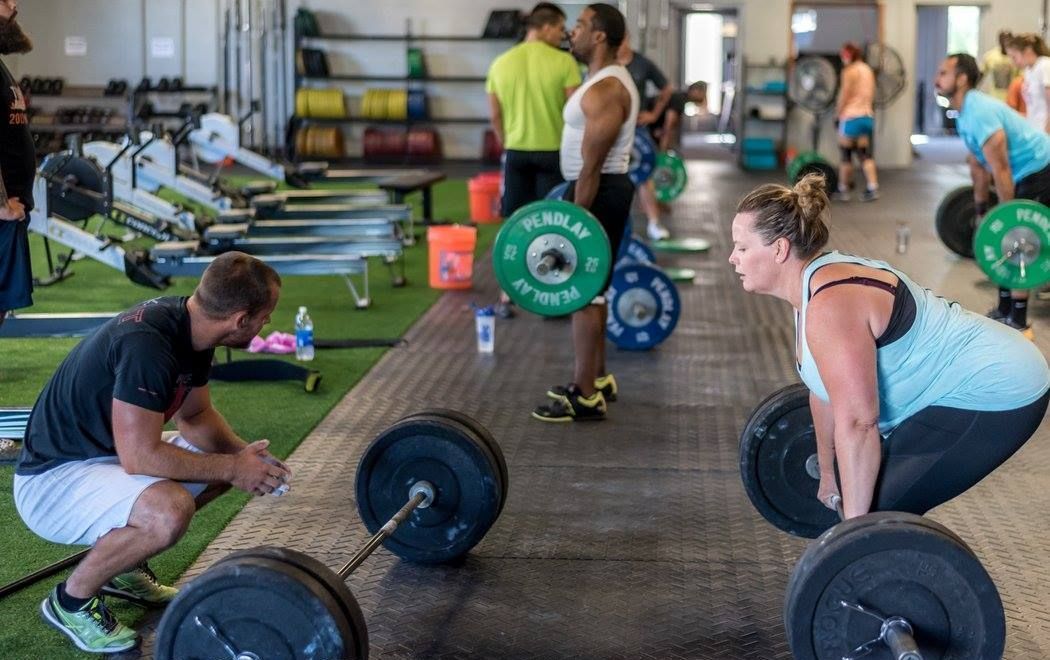 A group of people are lifting weights in a gym.